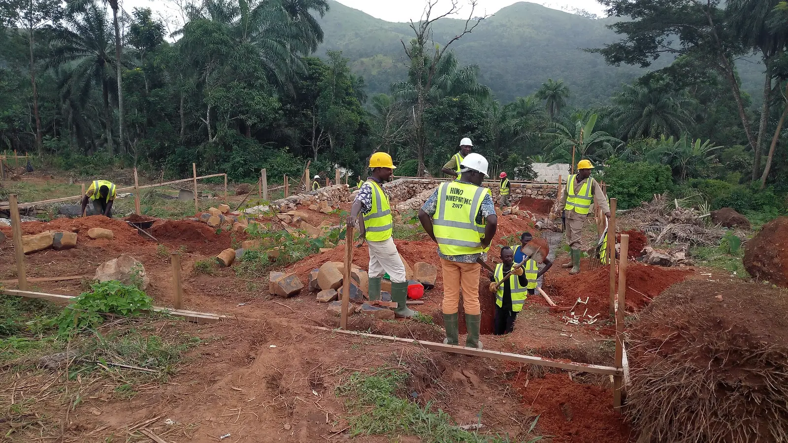Une équipe casquée sur l'implantation d'un chantier, en terre rouge